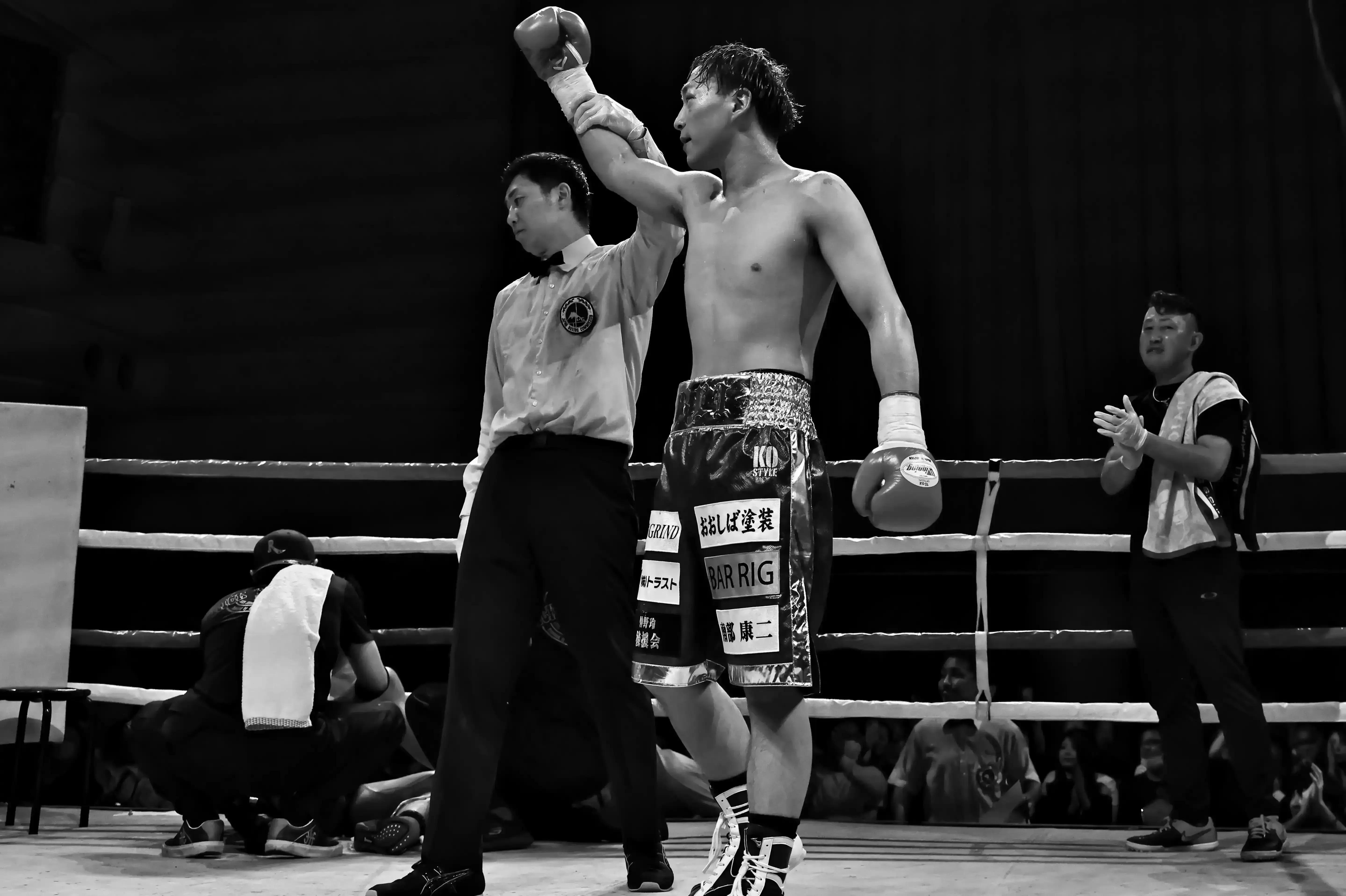レフェリーに手を上げられ勝利を宣告される選手(モノクロ)